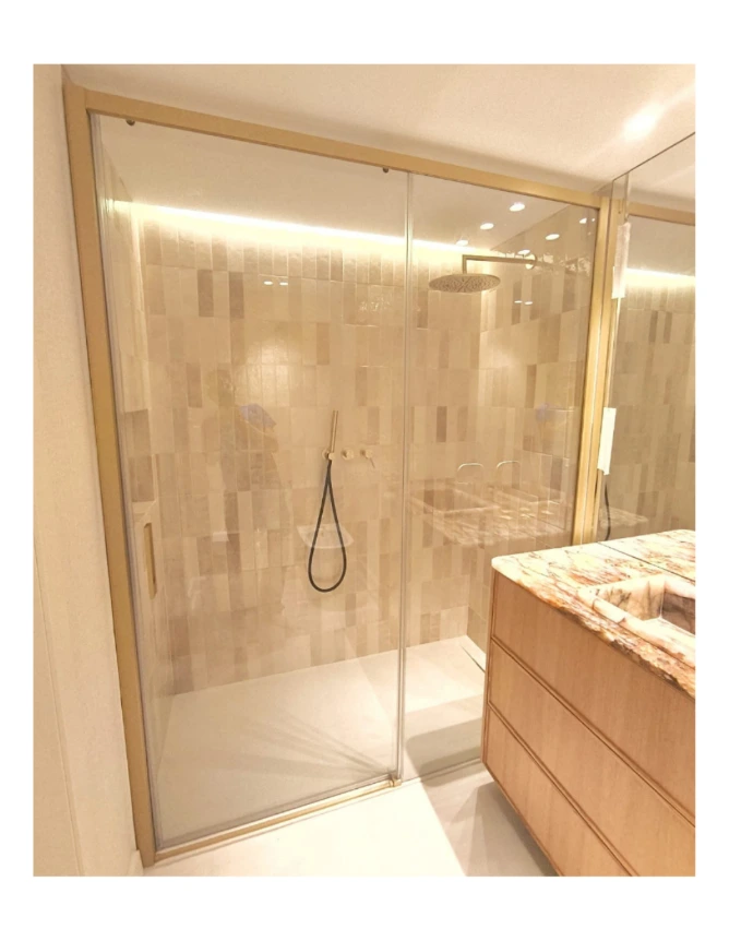 Mampara de ducha fijo y puerta corredera con perfiles en oro