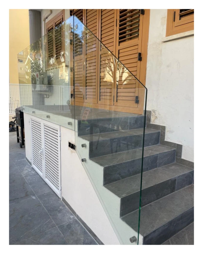 Barandilla de escalera para acceso de vivienda a terraza con soportes a pared y entre vidrios en plata