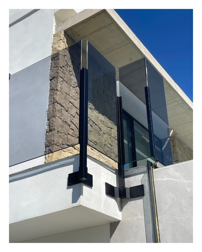 Barandilla para balcón de vivienda en vidrio gris y postes de anclaje negro mate