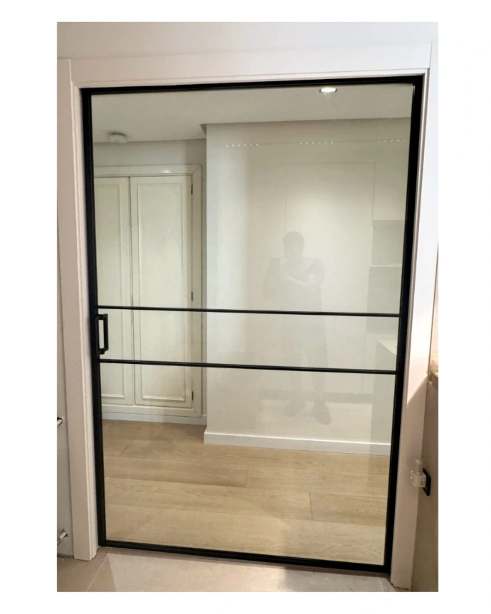 Puerta corredera en casoneto con vidrio incoloro y enmarcada en perfiles negros, decoración frame negro
