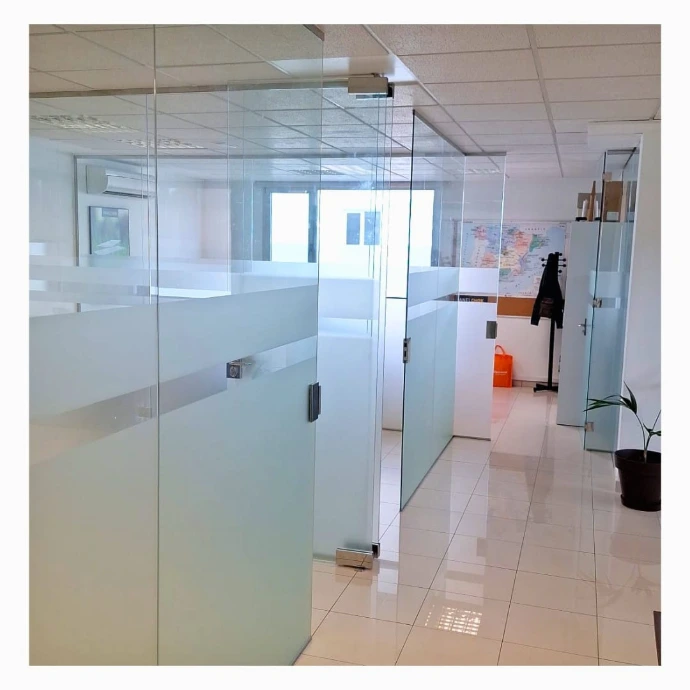 Divisoria oficina con vidrios fijos y puertas abatibles con cerradura con llave y vinilos