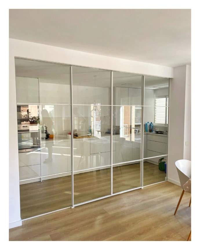 Divisoria compuesta por dos fijos y dos puertas correderas con guía a falso techo y vidrios incoloros con frame blanco